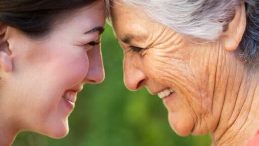 Smiling younger and older ladies touching foreheads