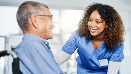 Shot of a young female nurse assisting a senior man in a wheelchair at a nursing home