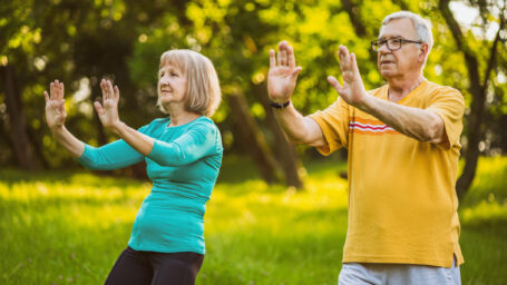 Senior couple is enjoying Tai Chi exercise in park.