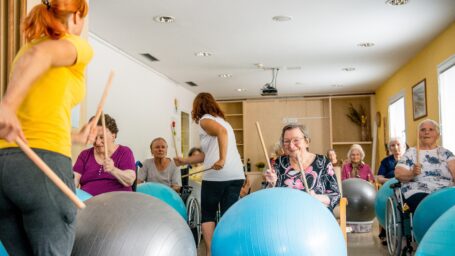 Drumming instructors teaching skills to audience using drumsticks and round rubber balls